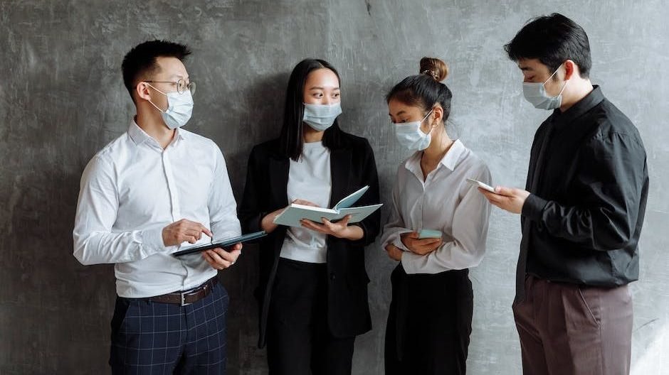 Team members discussing with each other while wearing masks in the office