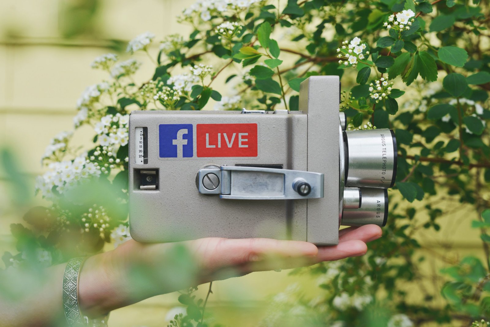 Someone holding a vintage-looking camera with a facebook live logo on it