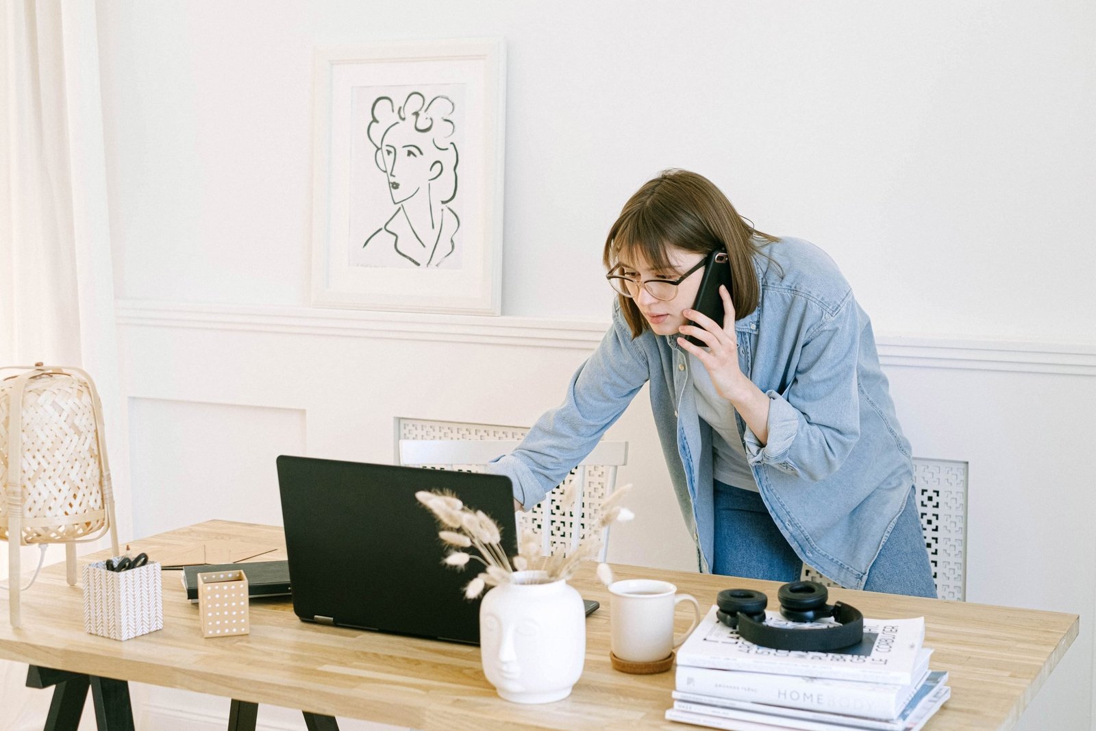 Busy woman speaking on the phone while looking at her laptop