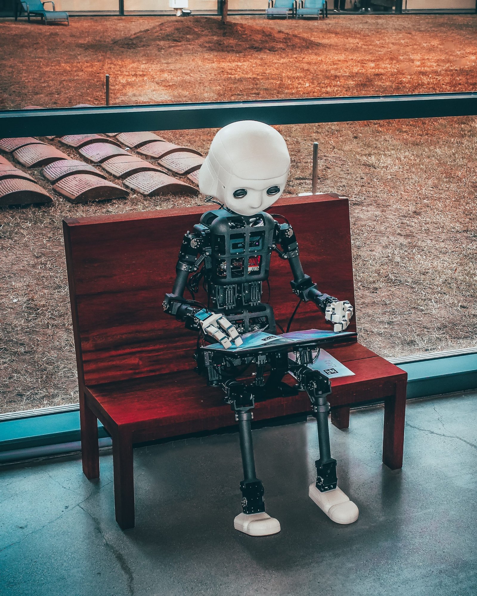 robot kid sitting on a bench and reading a book