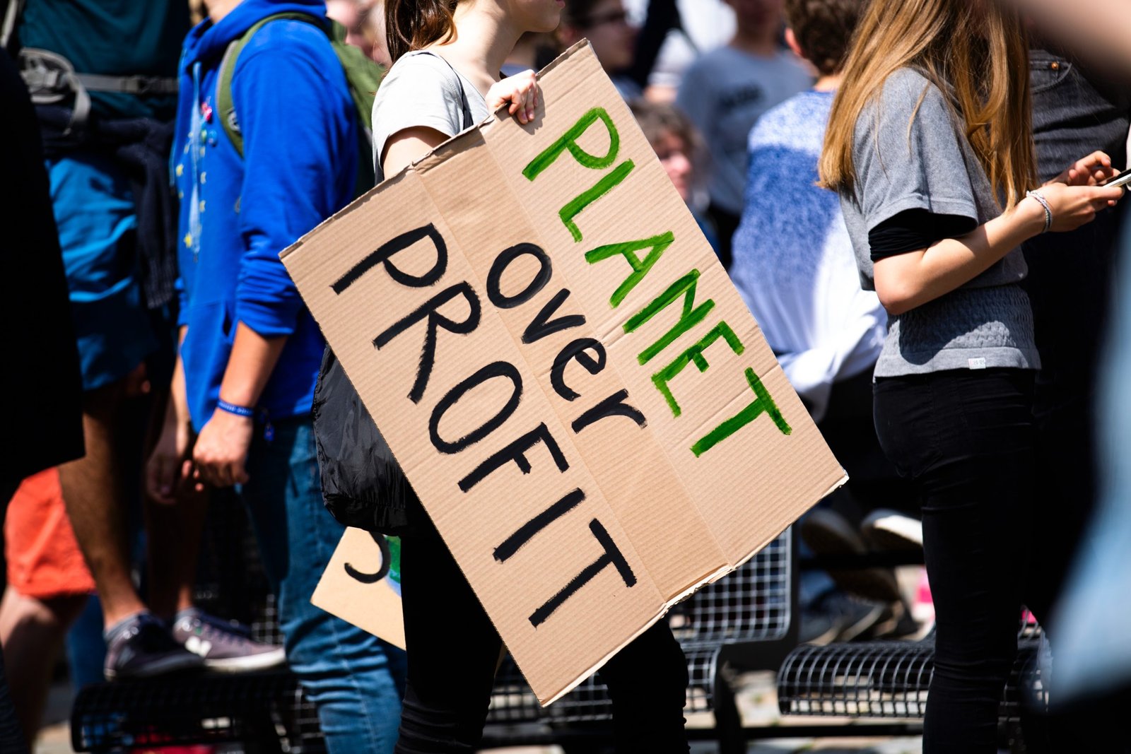 woman holding a sign that says 'planet over profit'