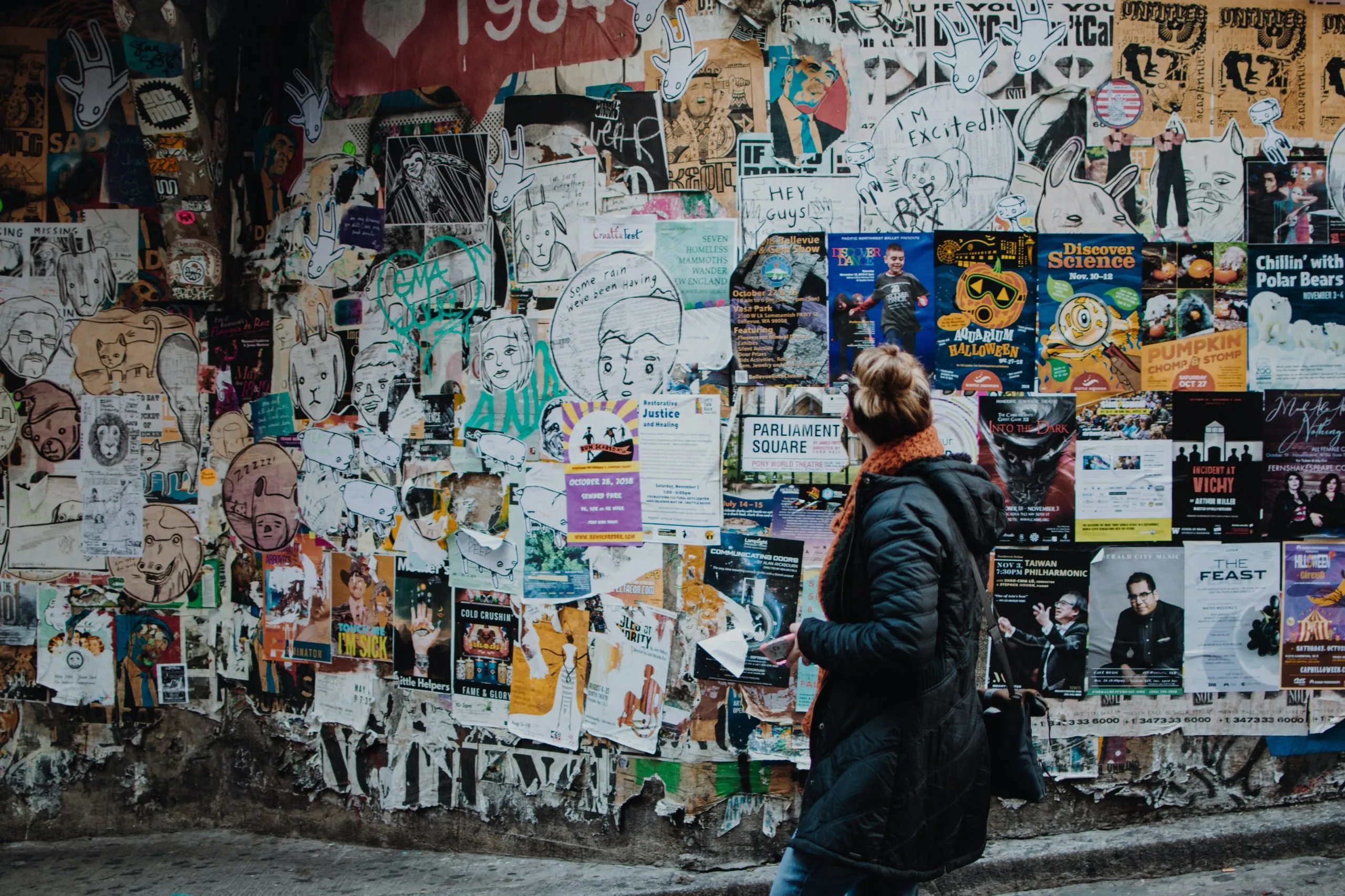 woman looking at a large wall full of posters and ads