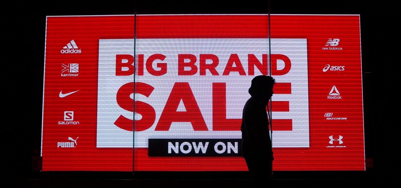 large digital billboard displaying a sale with the silhouette of a person walking in front of it