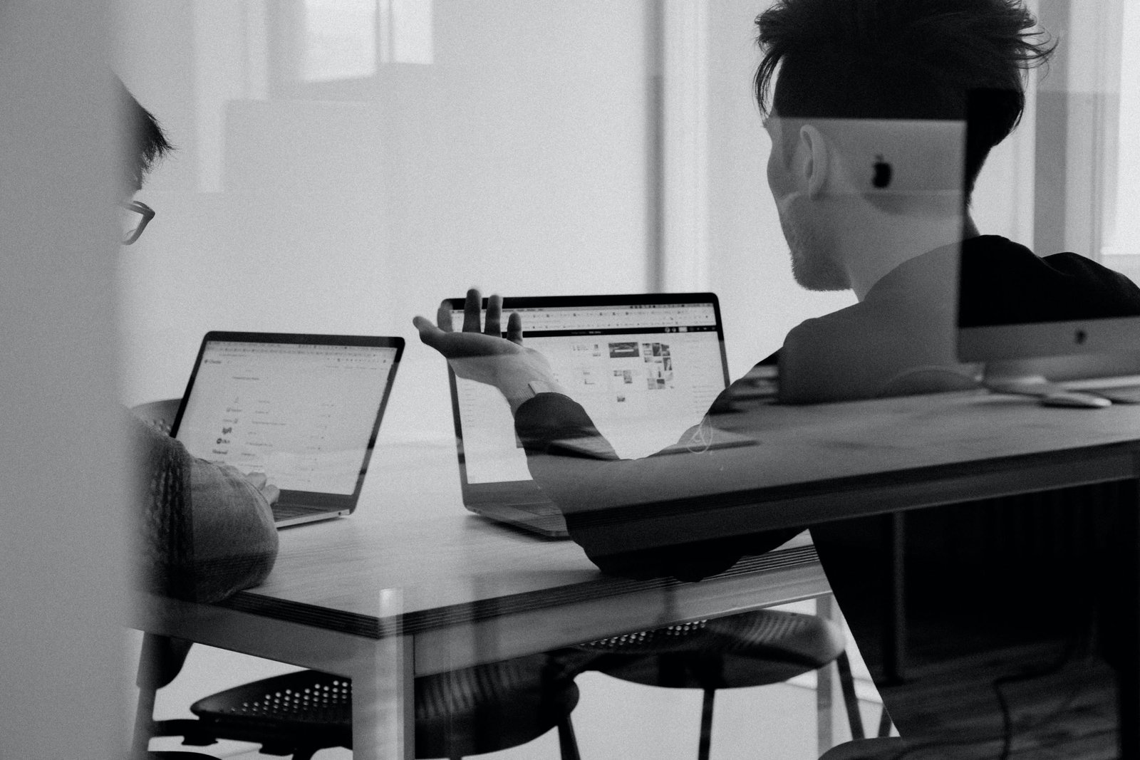 two people with laptops discussing in a meeting room