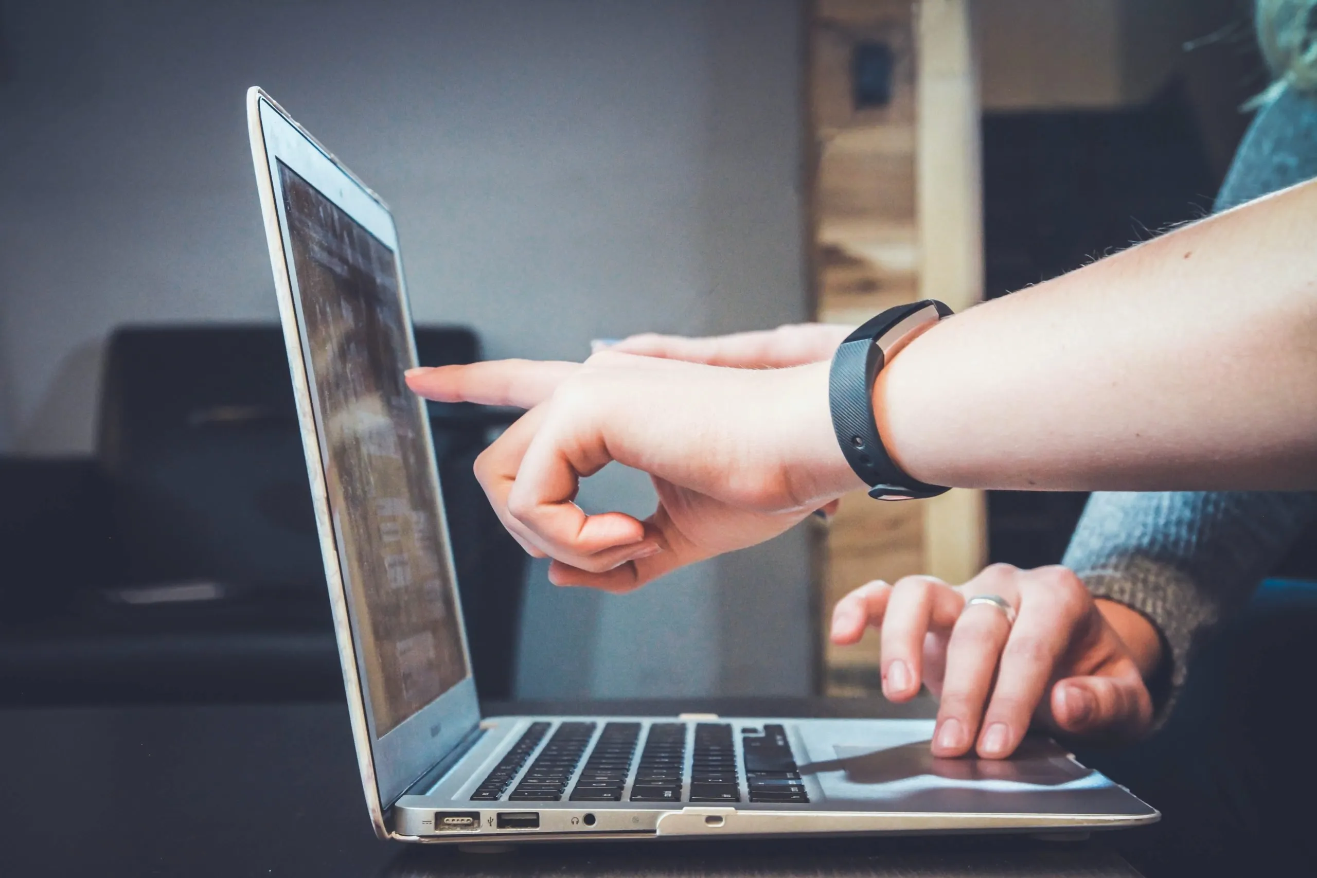 someone pointing something out on a laptop screen to someone