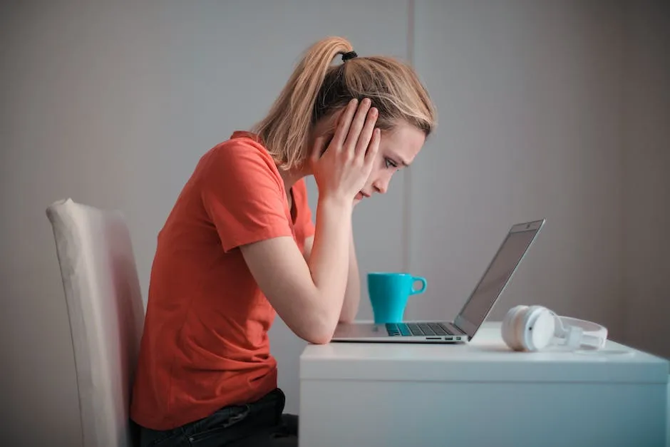 confused woman staring blankly at her laptop with hands on her head