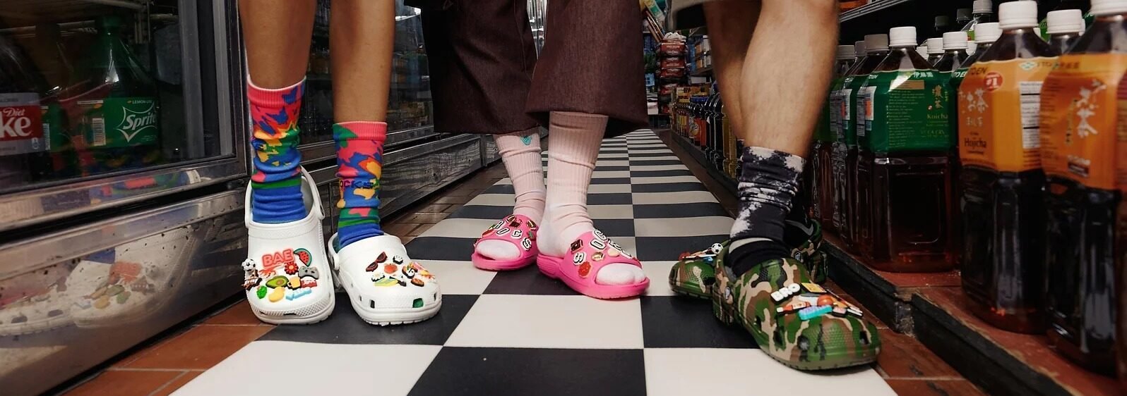 pairs of crocs and socks being modeled in a supermarket