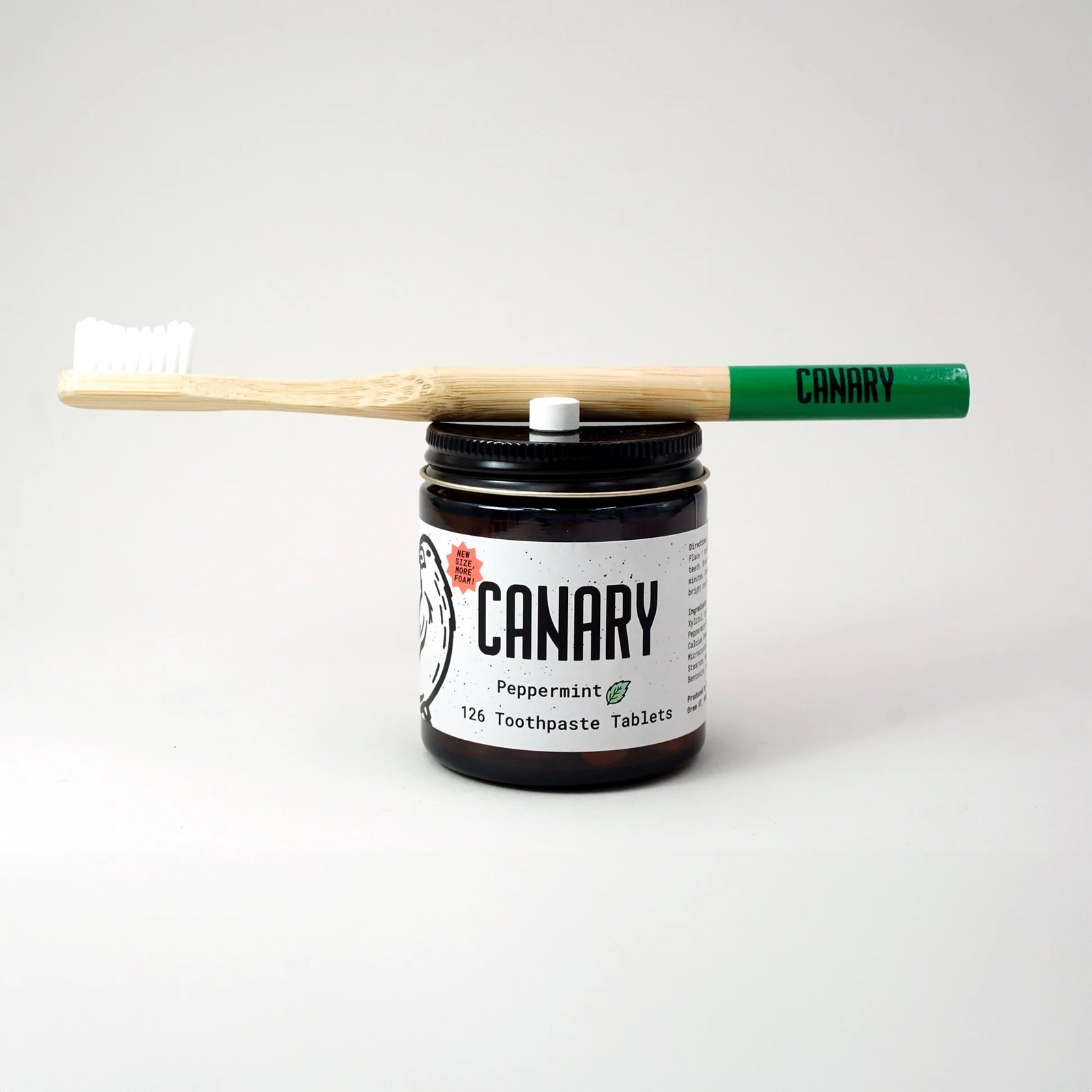 Canary Peppermint Toothpaste Tablets jar with a bamboo toothbrush on top.