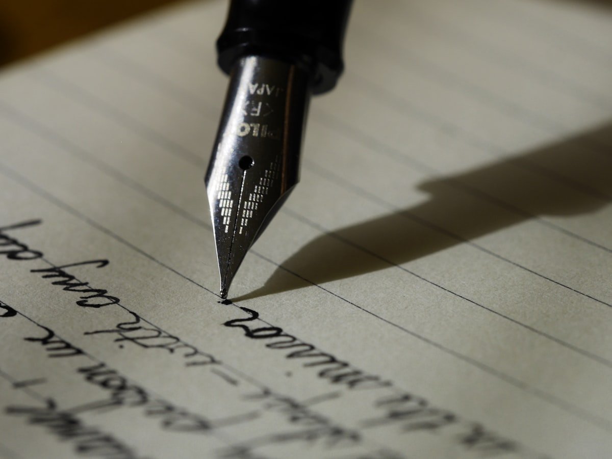 Close-up of a fountain pen nib writing on lined paper.